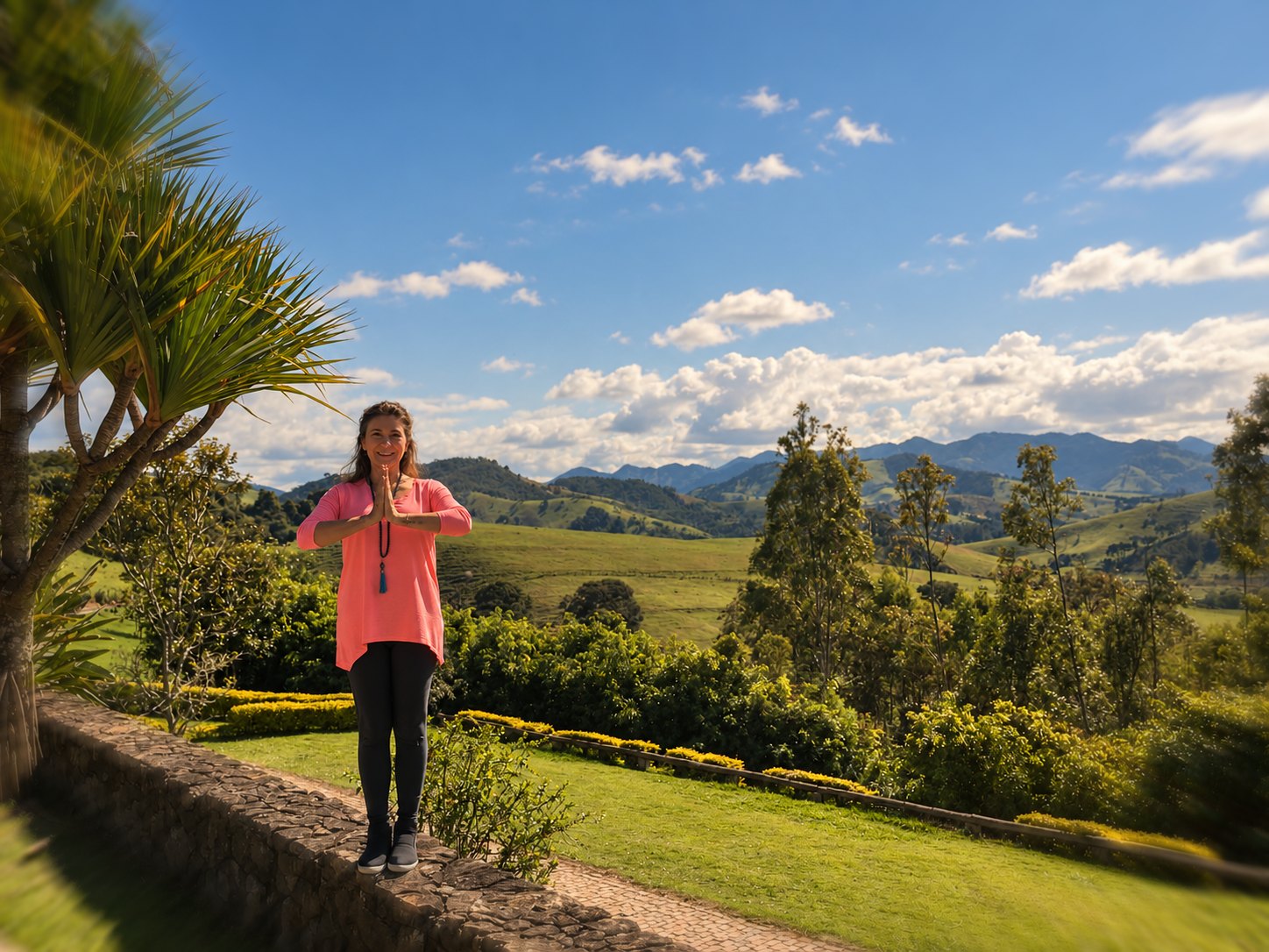 Vanessa em pé num jardim, diante das montanhas